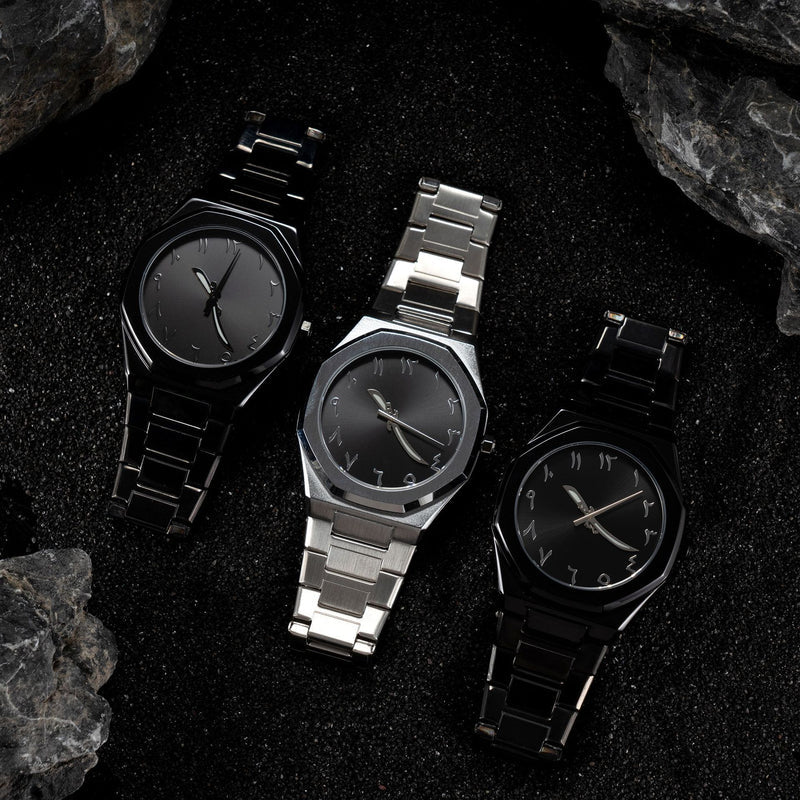 Three watches with black faces and metal bands on a dark textured surface.