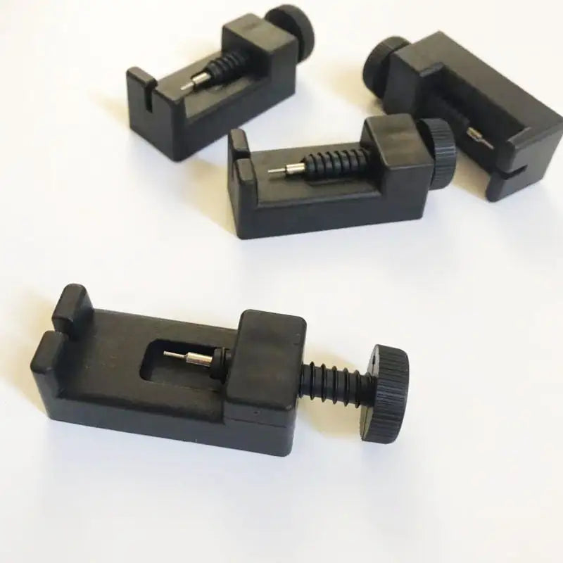 Four black metal clamps on a white background